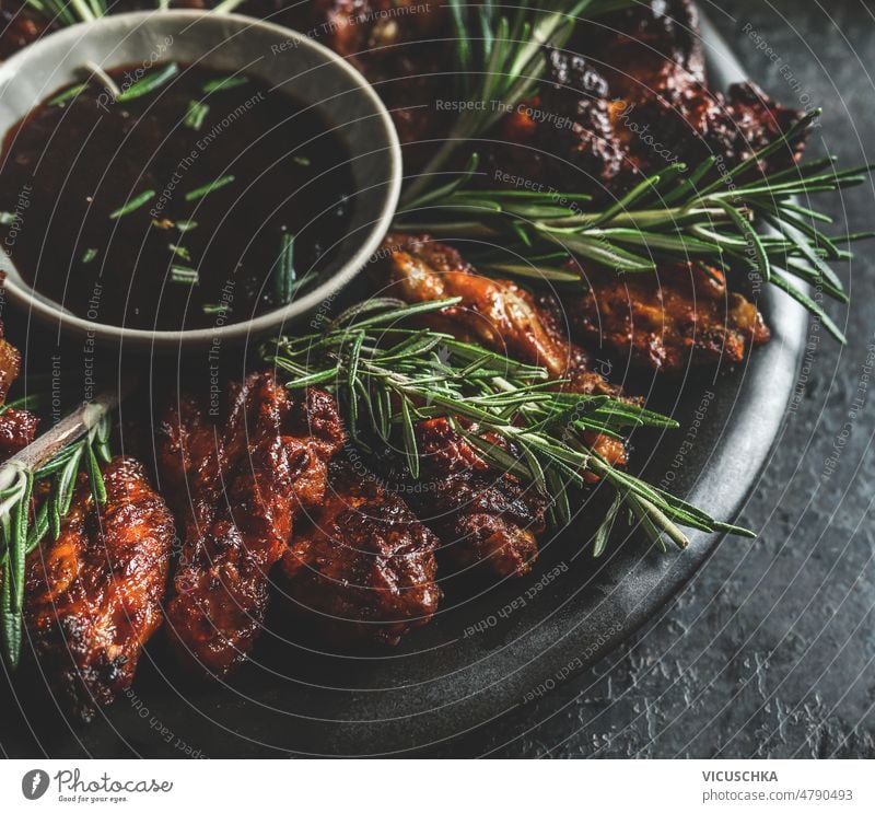 Close up of grilled chicken wings with rosemary and flavorful barbecue sauce on dark background. close up ready to eat front view american american food bbq