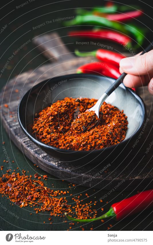 Chili powder spice in a black bowl chilli Powder seasoning Hand Spoon Rustic Ingredients Table Tangy Red Kitchen Pepper Organic Spicy Food flavor Component