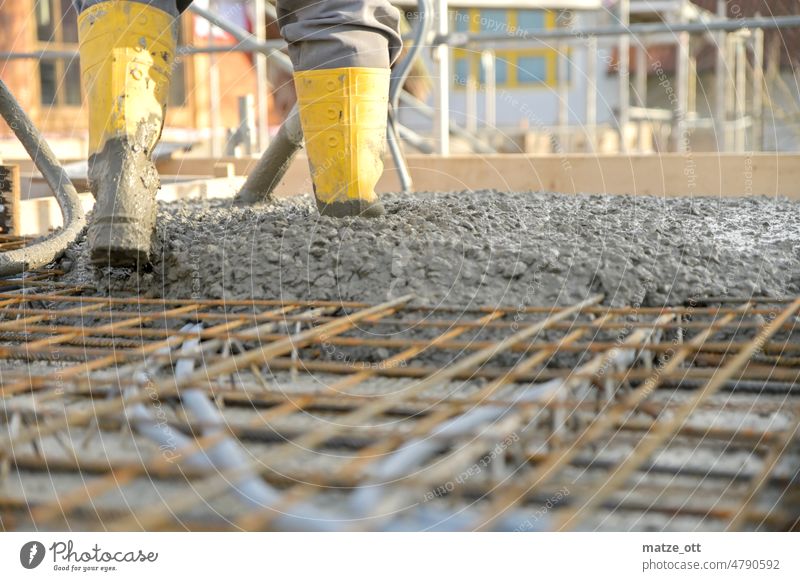 Construction worker on a building site pouring concrete Construction site Cement Concrete Rubber boots Craftsperson Working man Yellow Iron Metal House building