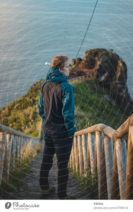Student wearing a jacket enjoys the view from Cristo Rei, Camara de Lomos, Madeira belonging to Portugal. Sunrise on the Atlantic coast. Discovering the European continent