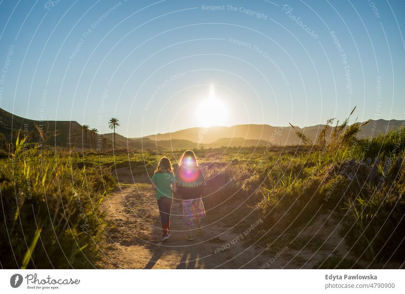 Two girls trekking in nature during sunset Playazo de Rodalquilar active activity adventure beautiful child childhood countryside day discovery explore