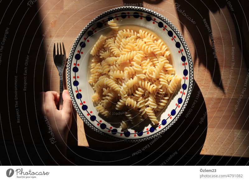 Fussiliteller in sunlight, on the left a child's hand and a fork Eating Noodles fussili Plate Kitchen Hot steam children's court Nutrition Lunch Italian Food