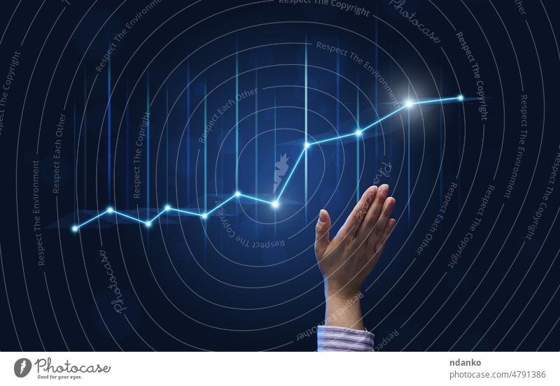 a businessman's hand points to a holographic graph with rising rates on a blue background. Development of a business with high profits, the prospect of implementing business plans