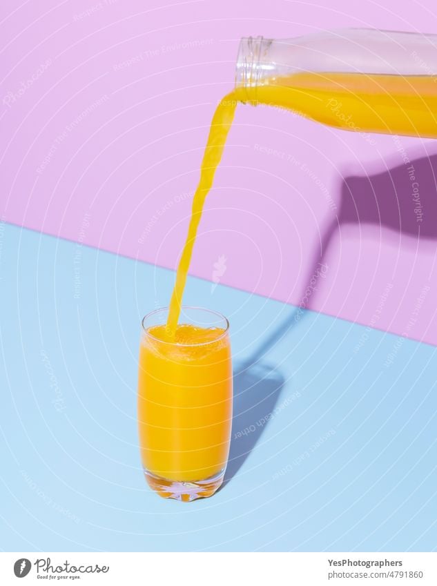 Orange juice glass on a blue table. Pouring orange juice. background beverage bottle breakfast bright citrus close-up color colorful cyan delicious drink drip