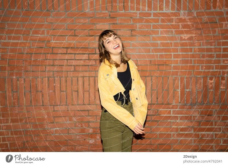 Young woman stands near an old brick wall in the city at night young standing attractive smiling happy casual attire female person beautiful lifestyle