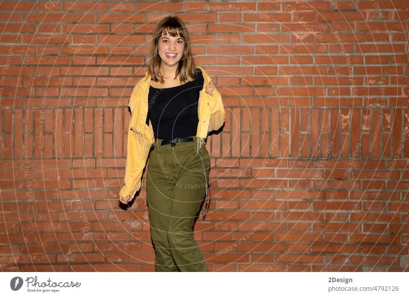Young woman stands near an old brick wall in the city at night young standing attractive smiling happy casual attire female person beautiful lifestyle