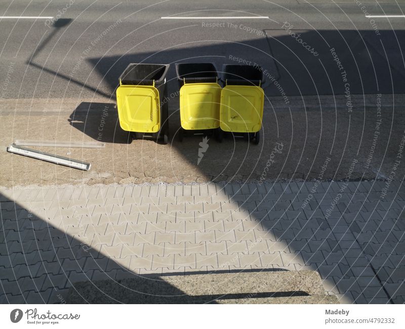 Waste garbage cans for recycling packaging with open yellow lid in the sunshine on the sidewalk in Oerlinghausen near Bielefeld on Hermannsweg in the Teutoburg Forest in East Westphalia-Lippe, Germany