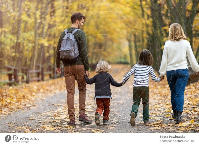 Parents with children on a walk in the park walking running leaf nature field autumn fall man dad father woman female mother family parents relatives son boy