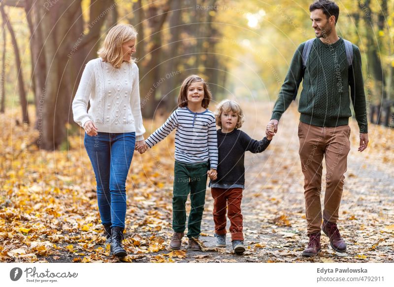 Parents with children on a walk in the park walking running leaf nature field autumn fall man dad father woman female mother family parents relatives son boy