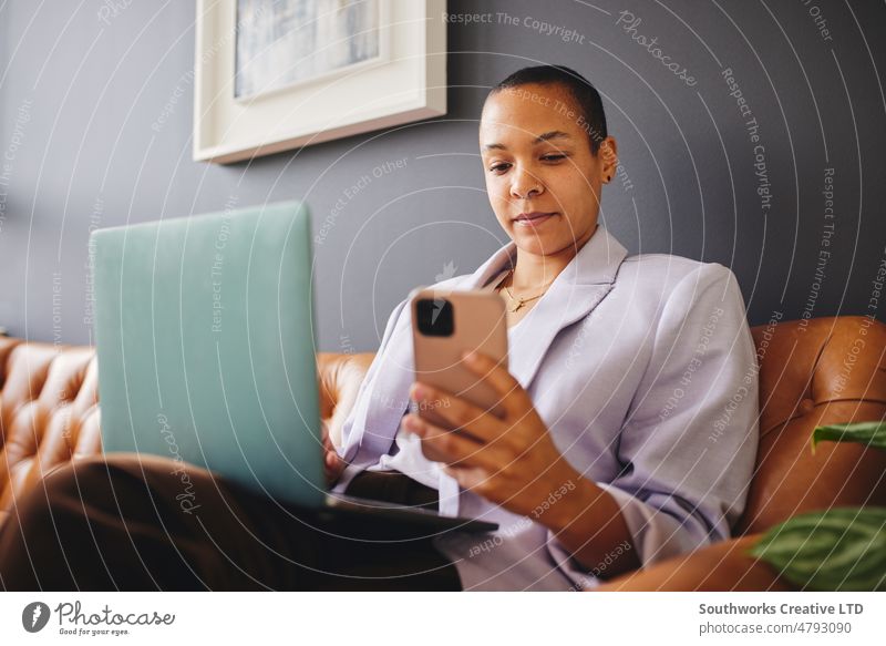 Portrait of multiracial LGBTQ mid adult woman using smartphone and laptop on couch and concentrating portrait lgbtq concentration business sofa leather