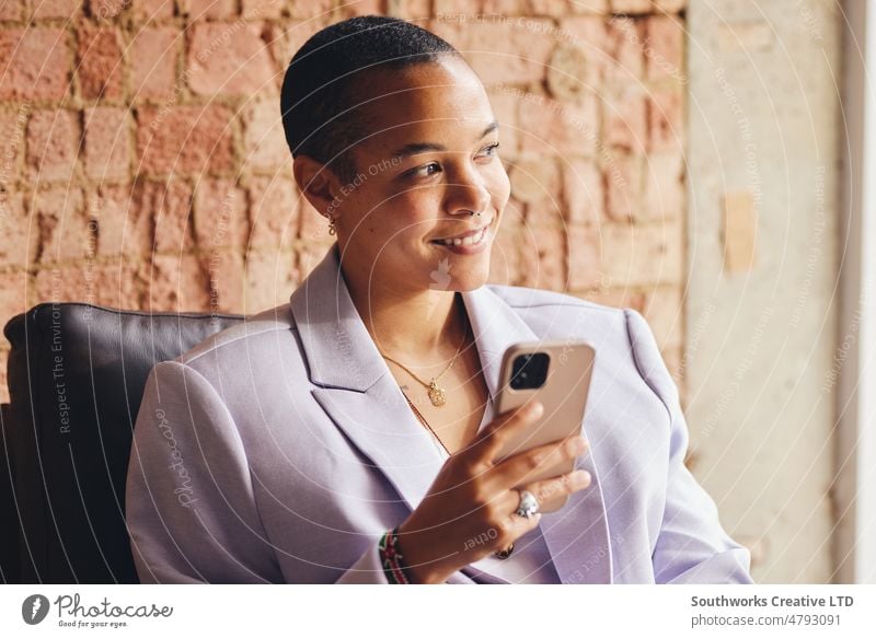 Portrait of multiracial LGBTQ mid adult woman using smartphone and smiling in front of exposed brick wall portrait lgbtq smile happy business confident indoors
