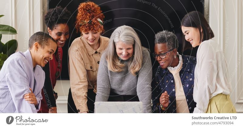 Portrait of cheerful multiethnic women in business meeting looking at laptop and smiling portrait smile teamwork six adult woman colleague coworker indoors day