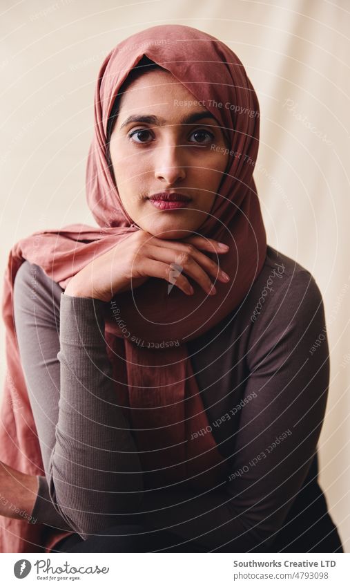 Portrait of young Muslim woman wearing hijab looking towards camera with hand on chin portrait muslim middle eastern one pride confident