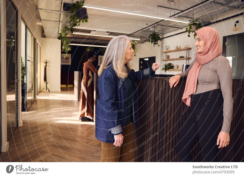 Portrait of multiethnic businesswomen having casual meeting in open plan office space, Muslim woman wearing hijab and smiling portrait businesswoman senior