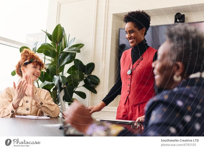 Portrait of mature black businesswoman in meeting with female colleagues smiling and being applauded portrait smile clap multiethnic teamwork three adult