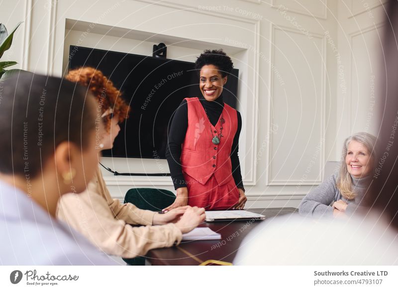 Portrait of cheerful mature black businesswoman listening to female colleagues in meeting room and smiling portrait smile discuss leadership boardroom