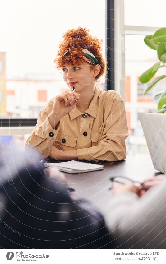 Portrait of pensive young white businesswoman listening and holding pen in meeting room portrait contemplation boardroom colleague one adult indoors day people