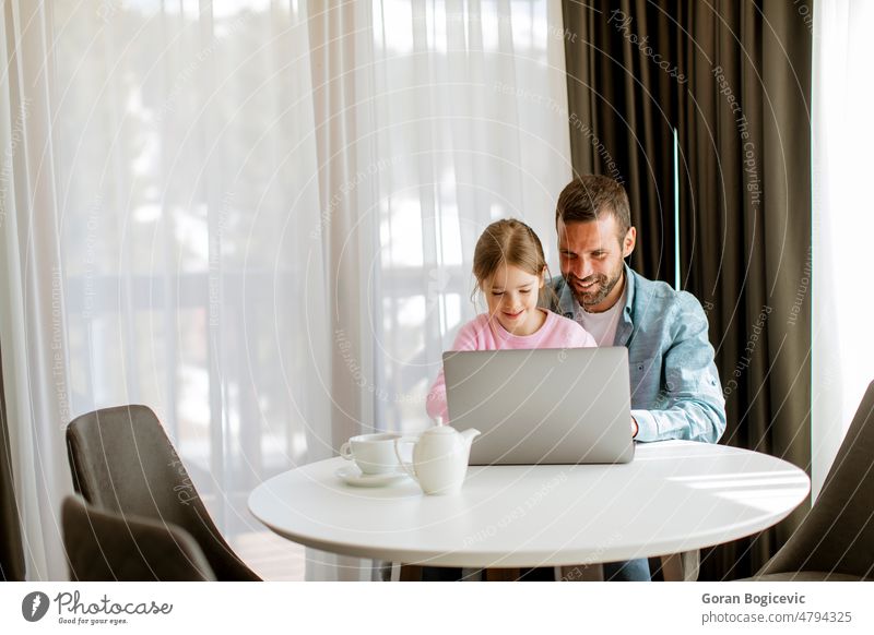 Father and daughter using laptop computer together adult browsing child childhood comfortable communication dad family father girl happy home indoors