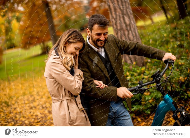 Young couple in the autumn park with electrical bicycle attractive autumnal beautiful boyfriend casual color date dating day e bicycle e bike ebike