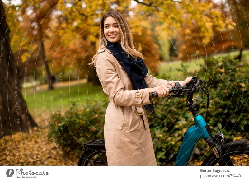 Young woman with electric bicycle in te autumn park active activity battery bike biker biking casual caucasian city color cyclist day e-bike ebike electrical