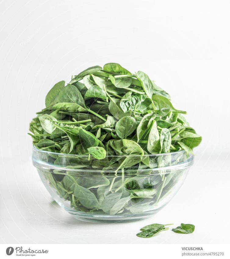 Heap of raw green spinach leaves in glass bowl at white background. heap healthy vegetable ingredient salad preparation front view vegetarian cooking food fresh