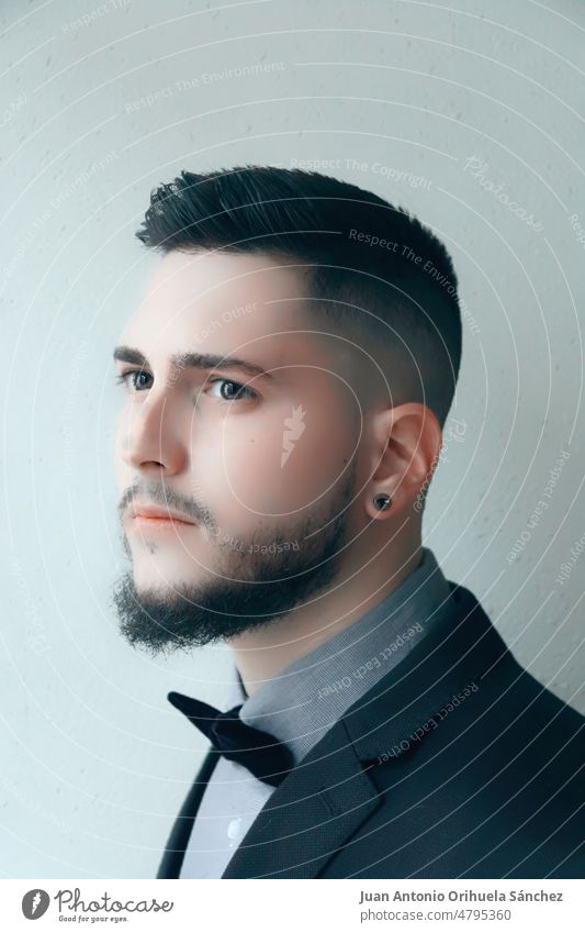 Portrait of a handsome hipster in a suit with a bow tie fashion man style elegant guy beard face expression young adult person portrait serious cool hispanic