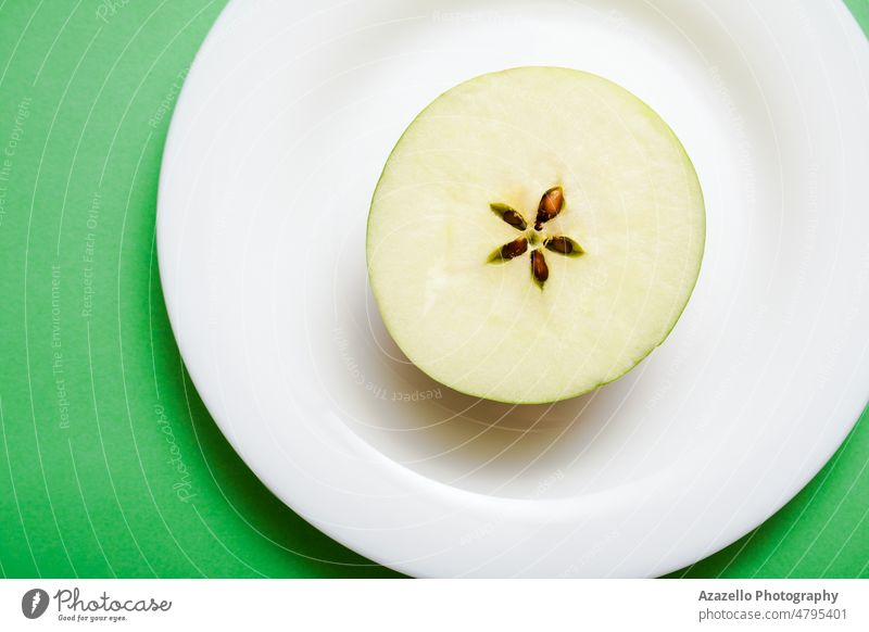 White plate with an apple half on green background. blue ceramic close up creative delicious design detail diet piece dieting eating fitness flat lay food