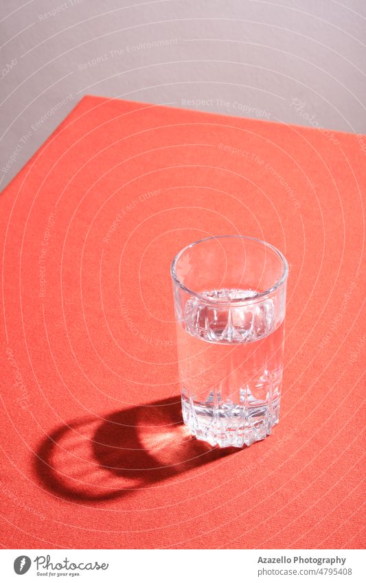 Glass of water with hard shadow on a table with red cloth. art still life tablecloth abstract material aqua beverage body clean clean water clear cold water
