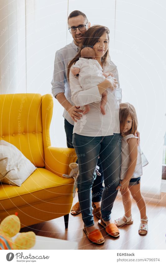 Family of four with newborn baby. mom dad older sister and little brother. family child person mother father daughter indoor together kid room sofa togetherness