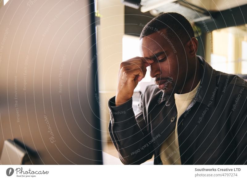 Stressed employee sat at office desk with workload burnout mental health stressed black businessman Mental illness depressed Male 30's mid adult