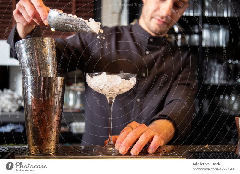 Crop barman filling cocktail glass with crushed ice in restaurant pour bartender prepare drink barkeeper scoop professional work shaker alcohol male young