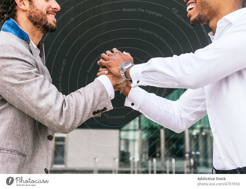 Anonymous happy multiethnic colleagues shaking hands businessmen handshake greeting entrepreneur urban building street formal style modern optimist coworker