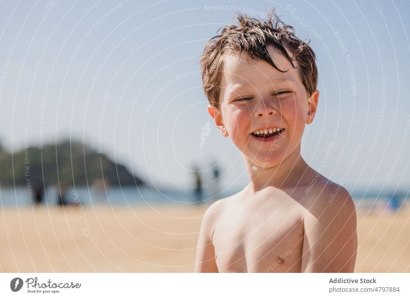Happy boy on sandy beach kid summer coast childhood rest pastime sea having fun cheerful positive smile happy content shore recreation naked torso shirtless