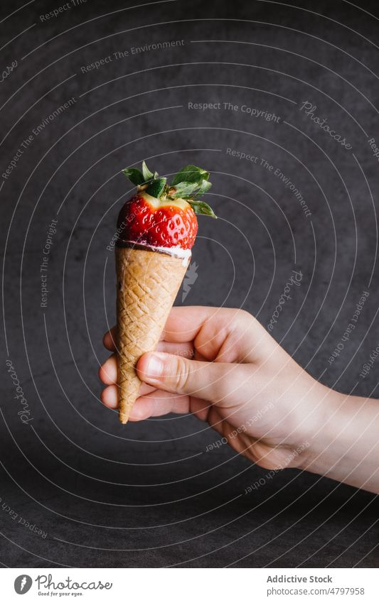 Anonymous person holding ice cream cone with strawberry sweet dessert treat indulge flavor product yummy delicious hand food cold fresh tasty ripe appetizing
