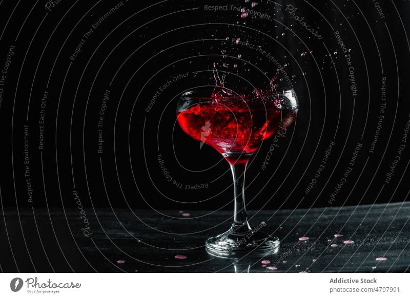 Splashing red wine in wineglass alcohol drink booze splash beverage aperitif flavor spill liquid goblet transparent table crystal taste fragile still life clear