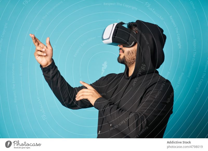 Man exploring virtual reality in headset man vr goggles cyberspace futuristic entertain explore immerse modern style casual informal trendy hoodie outfit studio