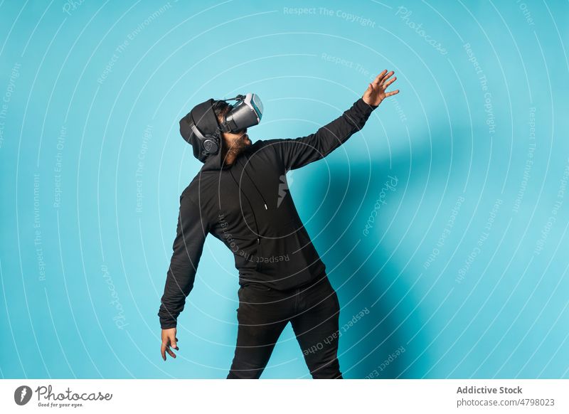 Man exploring virtual reality in headset man vr goggles cyberspace futuristic entertain explore immerse modern style casual informal trendy hoodie outfit studio