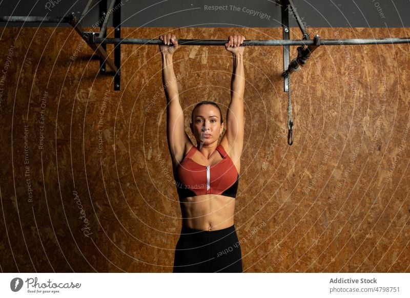 Focused sportswoman hanging on bar while working out in gym workout training athlete concentrate strong exercise energy fitness endurance female young