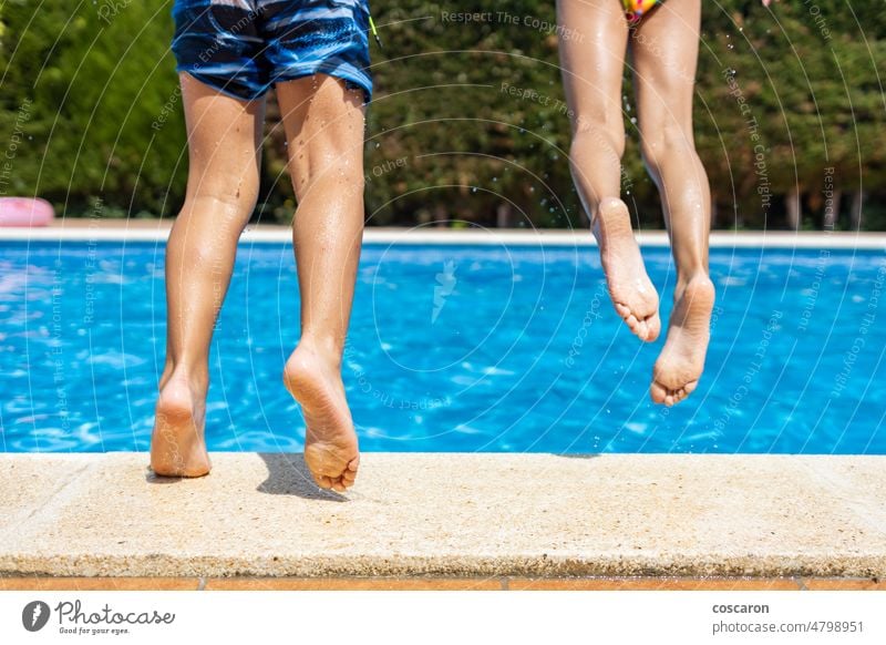 Two little kids jumping into a swimming pool. Leg detail activity beautiful blue child childhood edge feet foot freedom fresh fun girl happiness happy health