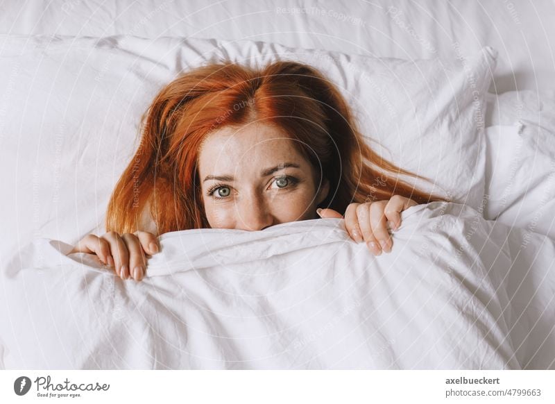 coy young woman hiding under bed cover girl duvet blanket shy playful happy smiling bedroom real people authentic home adult person lifestyle lady wellbeing