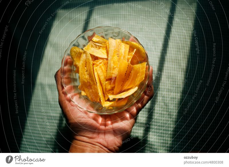 Hand holding banana chips on the bowl Close-up snack yellow fried slice background dry crunchy healthy ingredient vegetarian natural sweet many piece studio