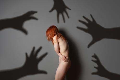 sexual harassment or abuse concept with naked woman shadows of grabbing hands assault violence rape fear person female problem bully depression emotion despair
