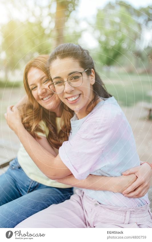 Two happy girlfriends embracing looking at camera smiling two two person smile glasses together hug affectionate hugging togetherness joy embrace friendship