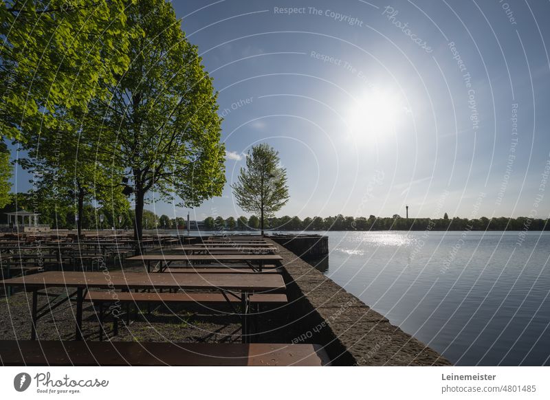 In a beer garden on an early Sunday morning in May at the Maschsee in Hannover Spring Beer garden trees Lake Empty benches tables Skyline bank Morning