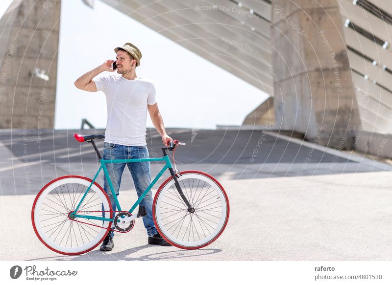 Outdoor portrait of handsome young man with mobile phone and fixed gear bicycle in the street. standing holding fixie person talking male urban bike outdoors