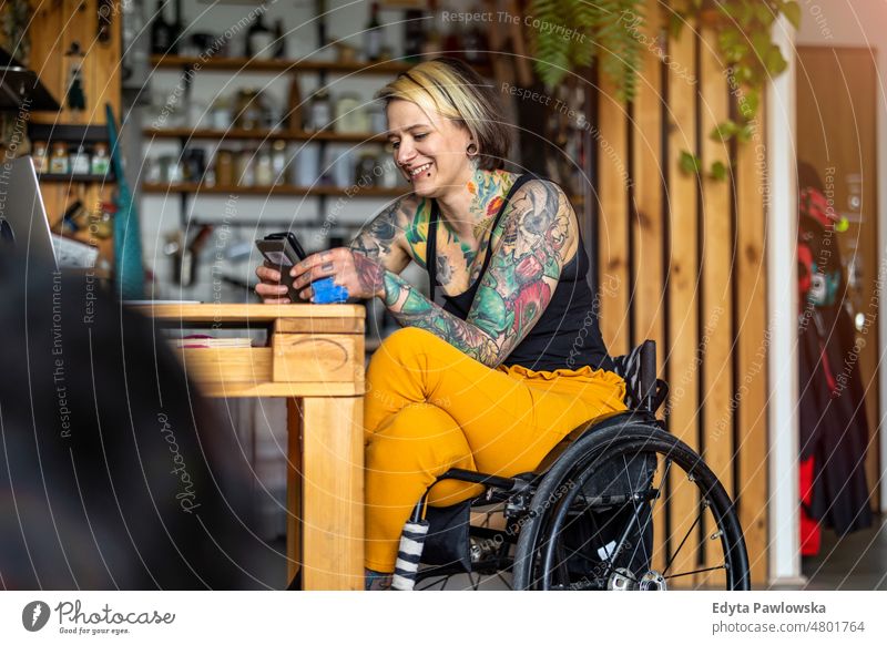Young Woman In Wheelchair using Smartphone At Home wheelchair domestic life confidence woman indoors home house people young adult casual female Caucasian