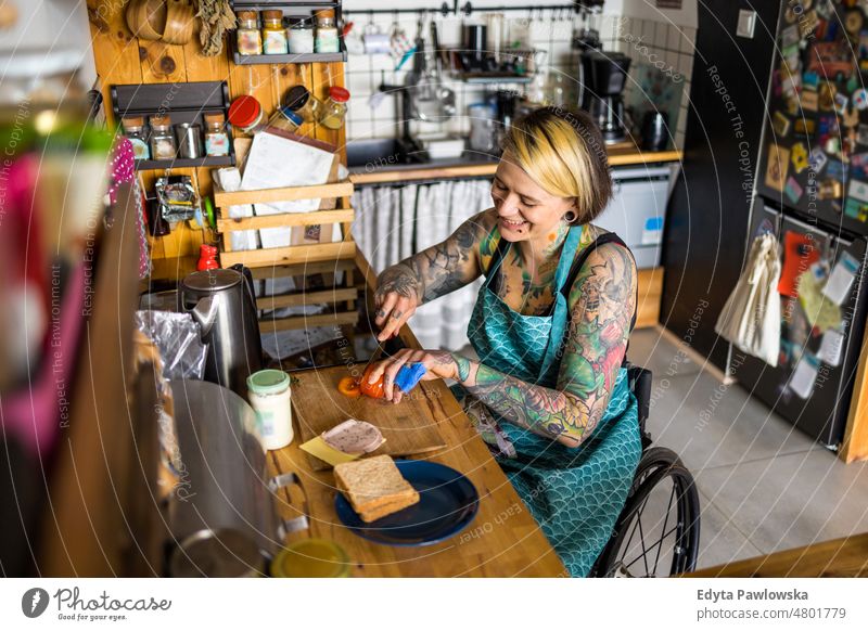 Woman in wheelchair preparing food in kitchen at home domestic life confidence woman indoors house people young adult casual female Caucasian attractive
