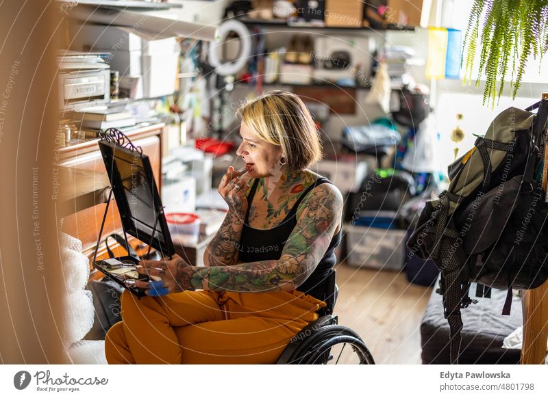 Young woman in a wheelchair doing her make-up at home domestic life confidence indoors house people young adult casual female Caucasian attractive beautiful