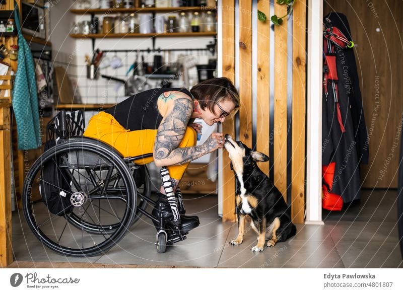 Young woman with disability with her dog at home wheelchair domestic life confidence indoors house people young adult casual female Caucasian attractive