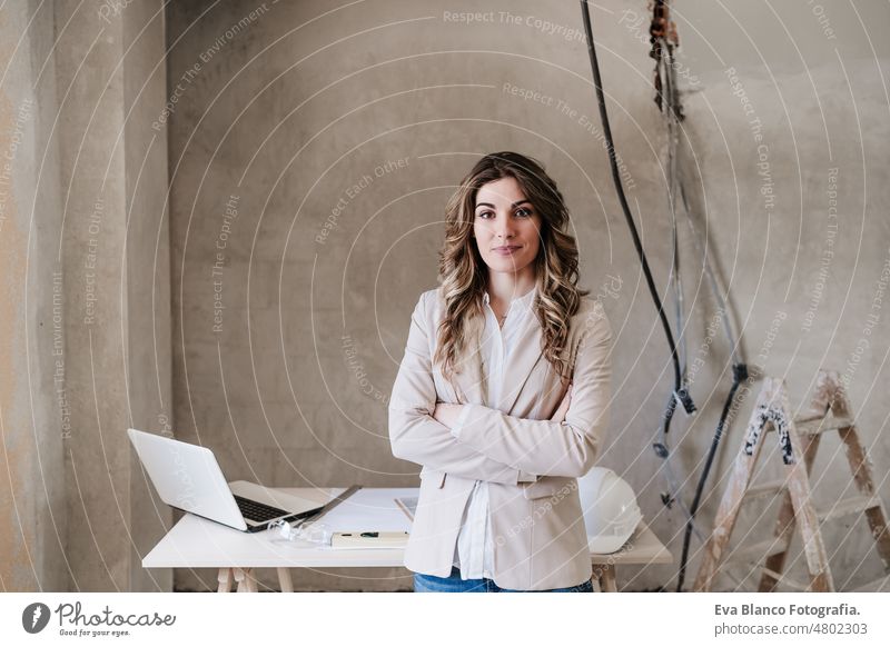 professional confident architect woman in construction site. Home renovation blueprints workspace protective helmet protective jacket mobile phone real estate